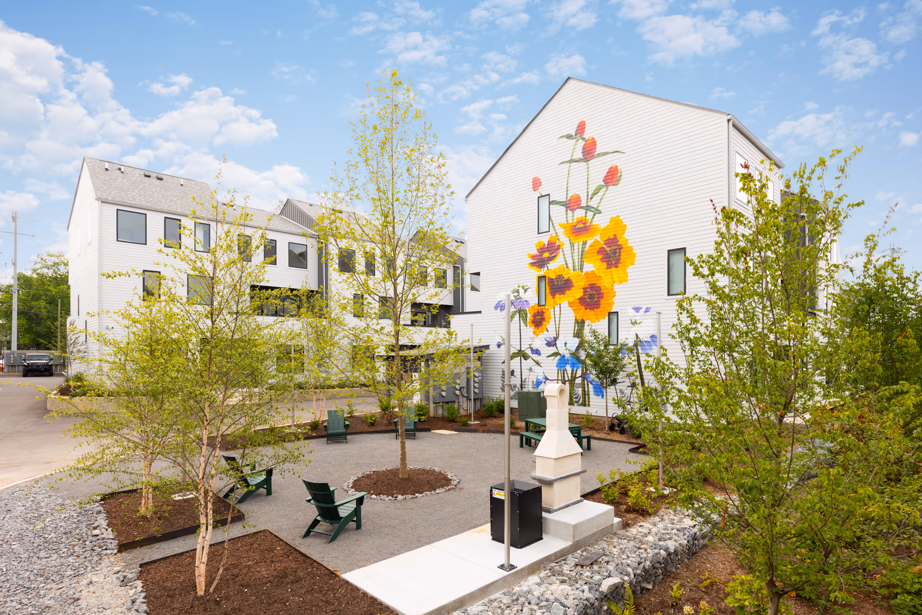 The outdoor garden and common sitting area between the residencies at Gardenia with a large flower mural on one of the buildings in the background.
