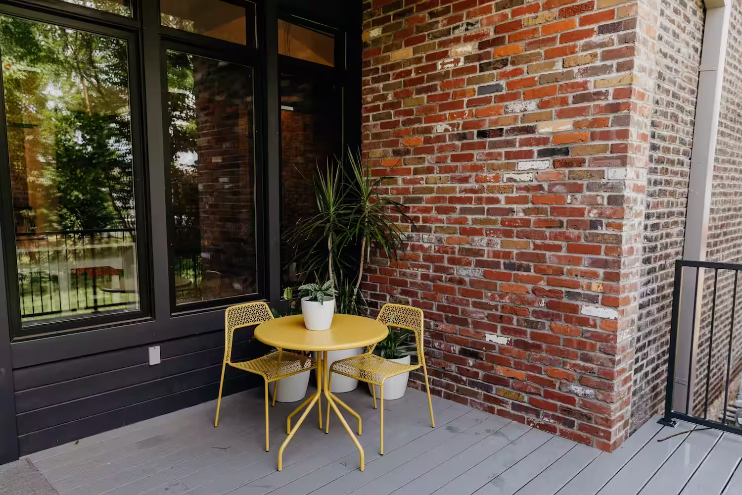 Outdoor patio area near a door with windows with a yellow metal able and chairs