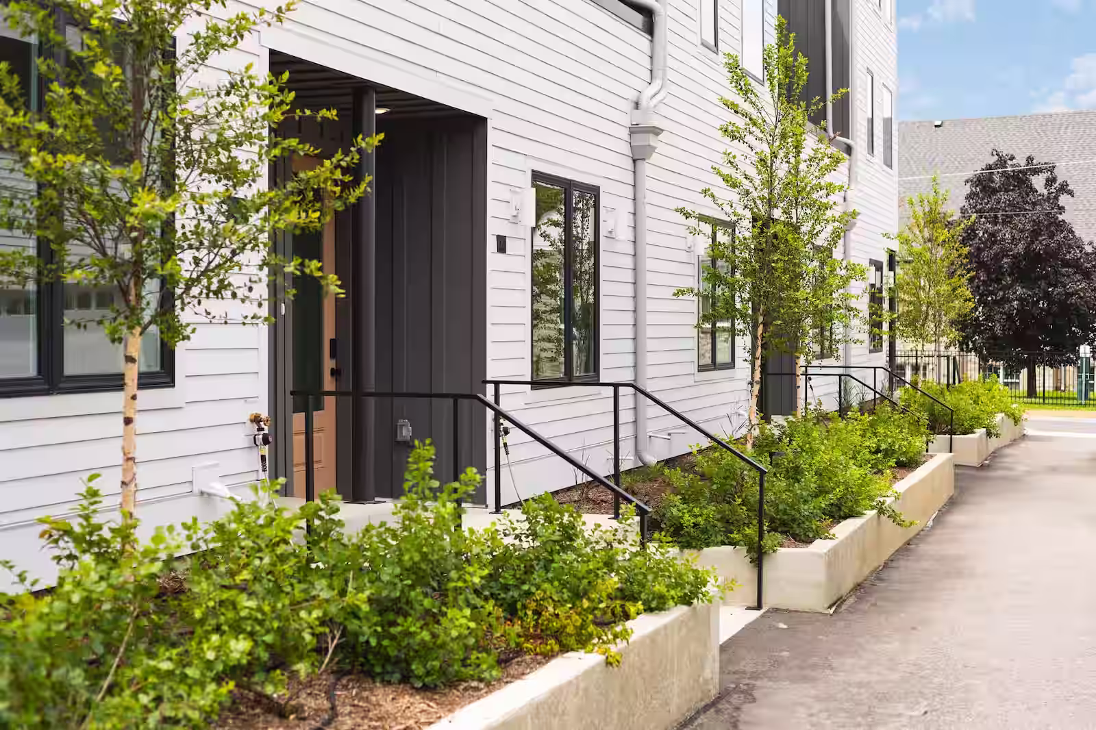Front entrance to a condominium with plants and trees in front of the door