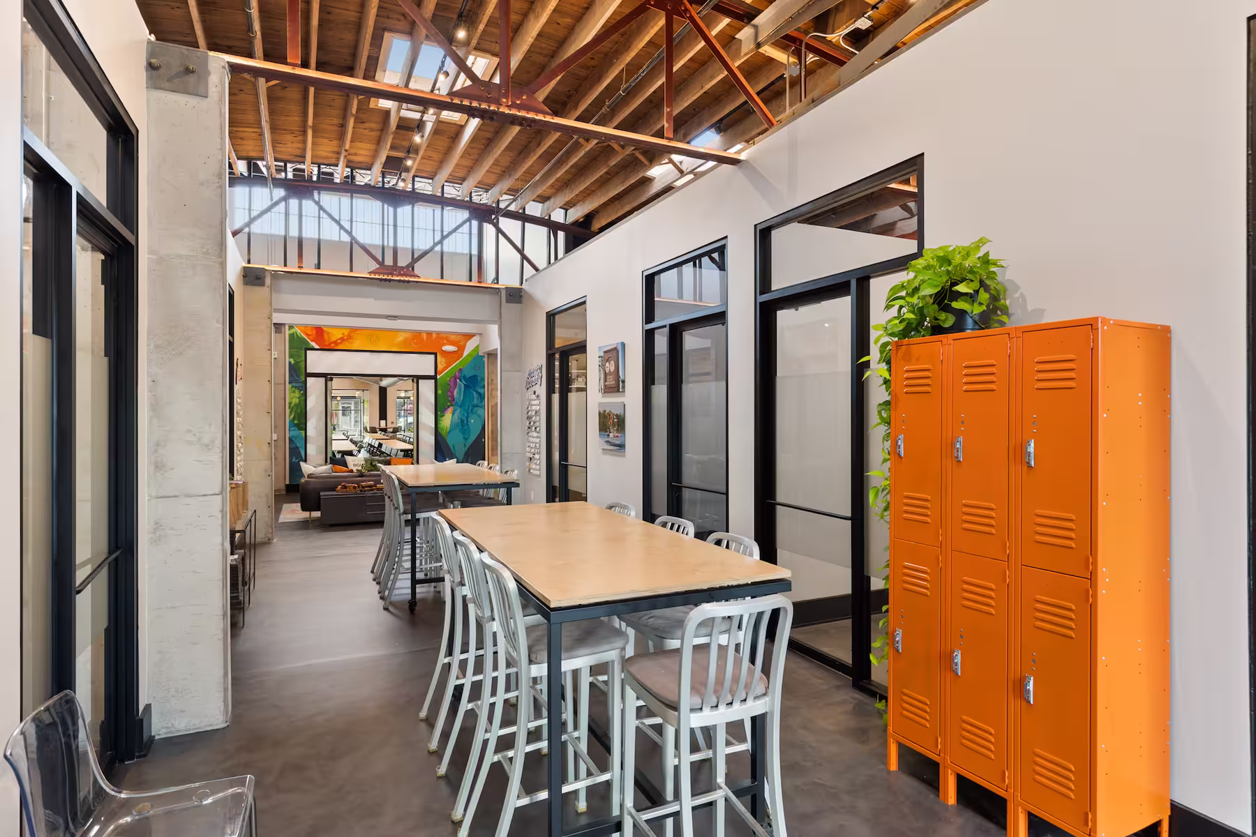 Common seating area with high chairs, a high table, and bright orange metal lockers.