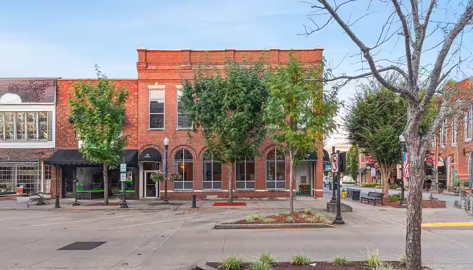 Brick office complex at the intersection between two roads with trees in front of it.