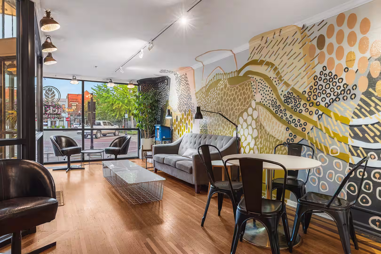 Common seating area with a large abstract painted mural on the wall and a large window facing the street