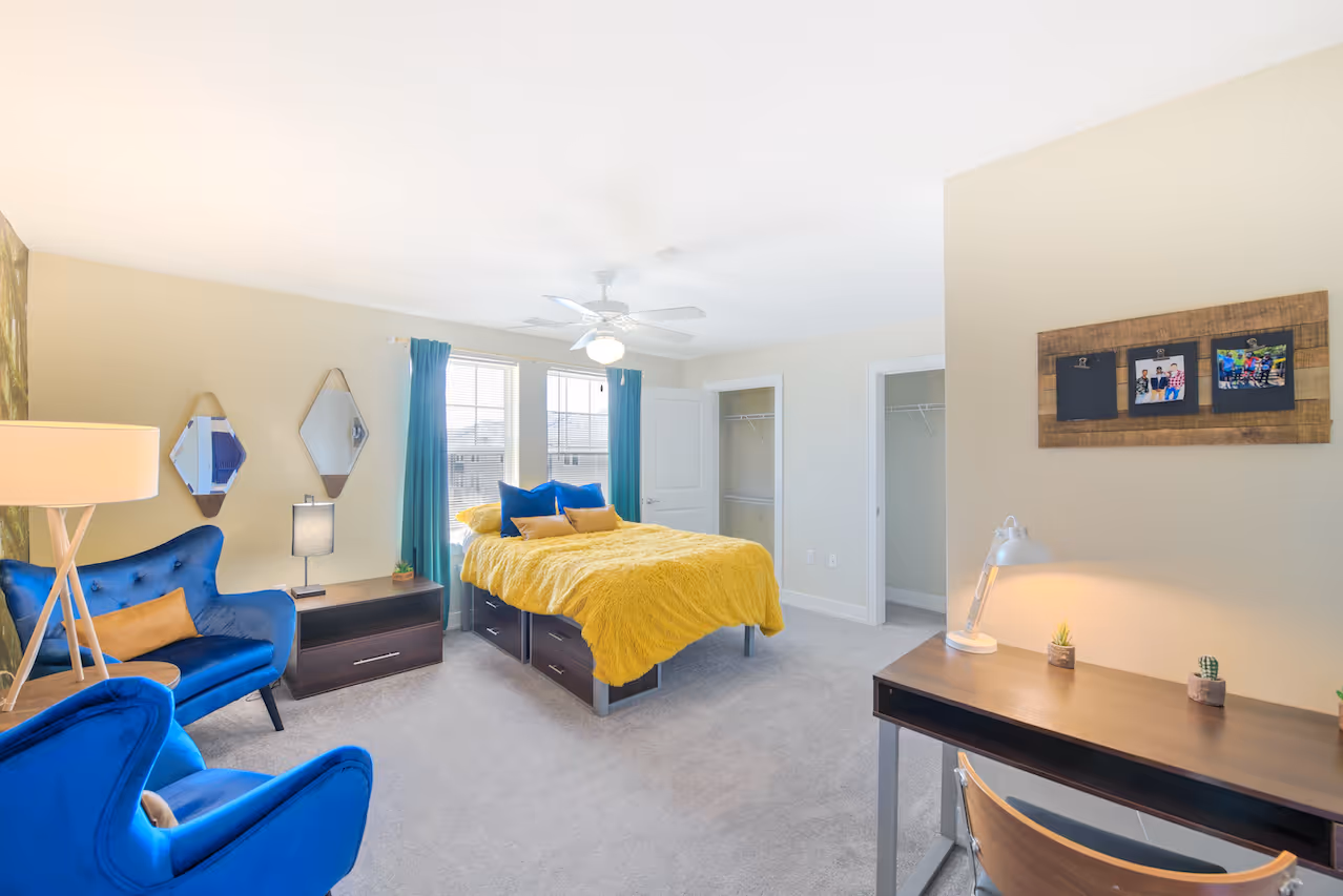 Fully furnished bedroom with seating area and desk 