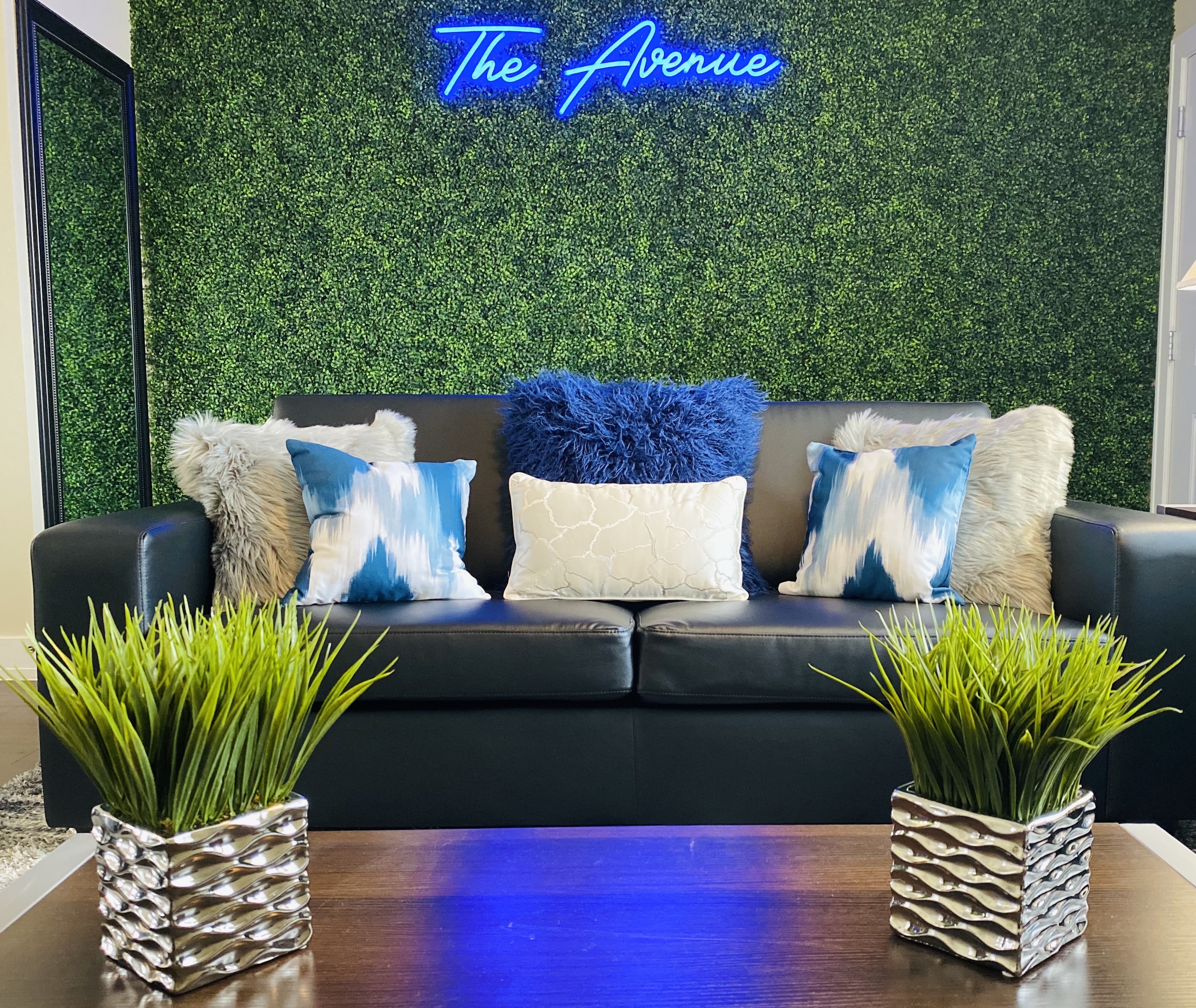 Straight on view of couch with pillows in front of greenery accent wall
