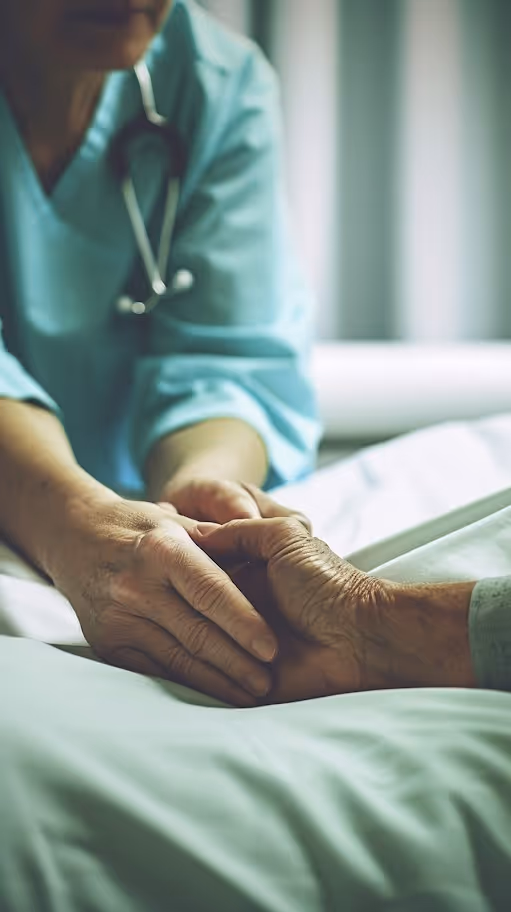 Manos de un profesional de la salud sosteniendo y brindando apoyo a las manos de un paciente en una cama.