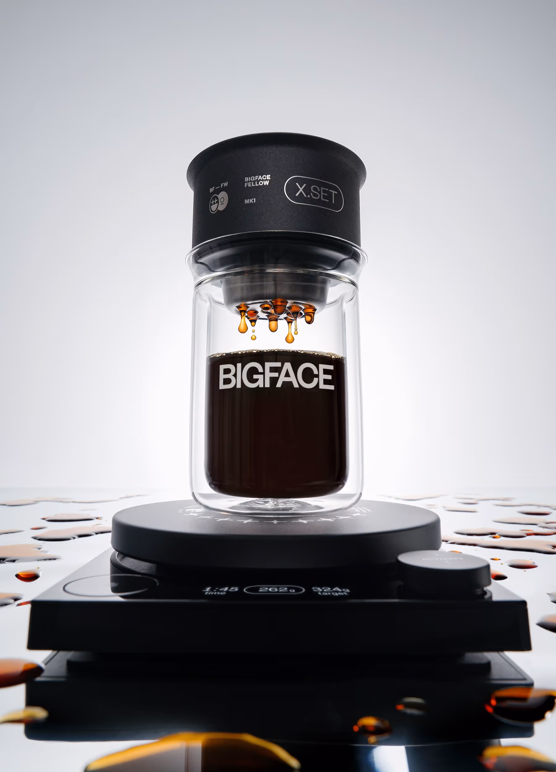 Glass coffee brewer labeled BIGFACE with coffee dripping into a glass container on a digital scale.