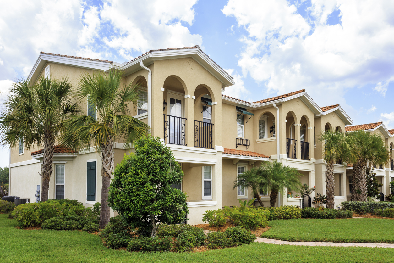 Neighborhood of condominiums in a row. Palm trees, front lawn, tropical climate.