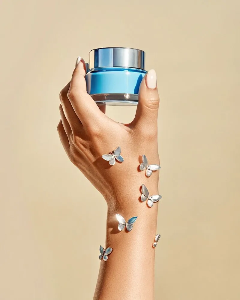 A woman's hand holding a blue cup with butterflies on it.