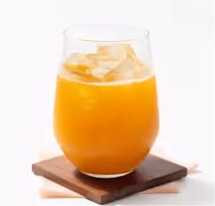 Glass of orange juice with ice cubes on a wooden coaster.