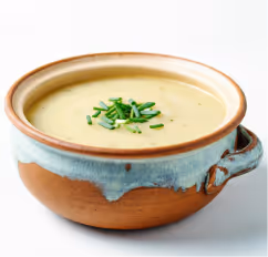 Creamy soup garnished with chopped chives in a ceramic bowl with a handle.