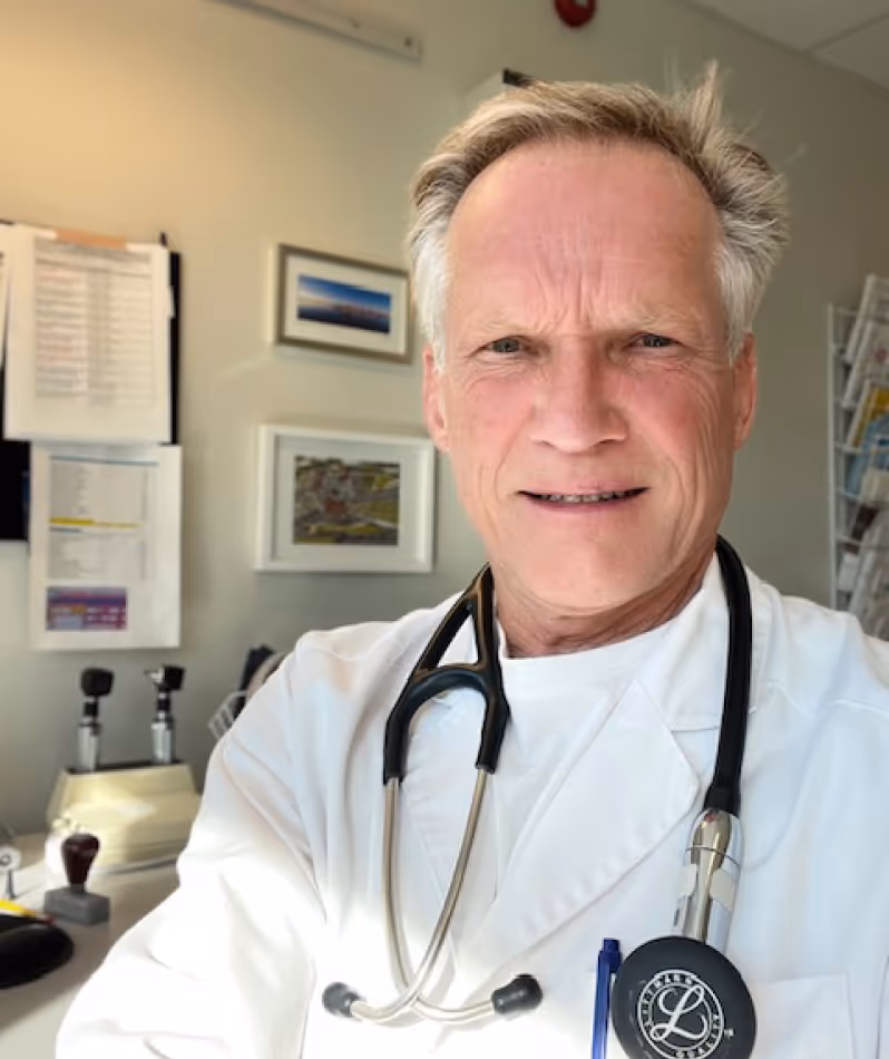 Male doctor wearing a white coat and stethoscope in a medical office.