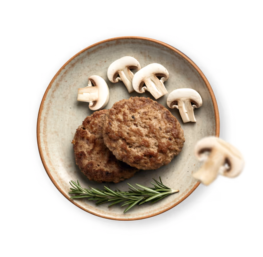 Two cooked sausage patties on a plate garnished with fresh rosemary and sliced white mushrooms.