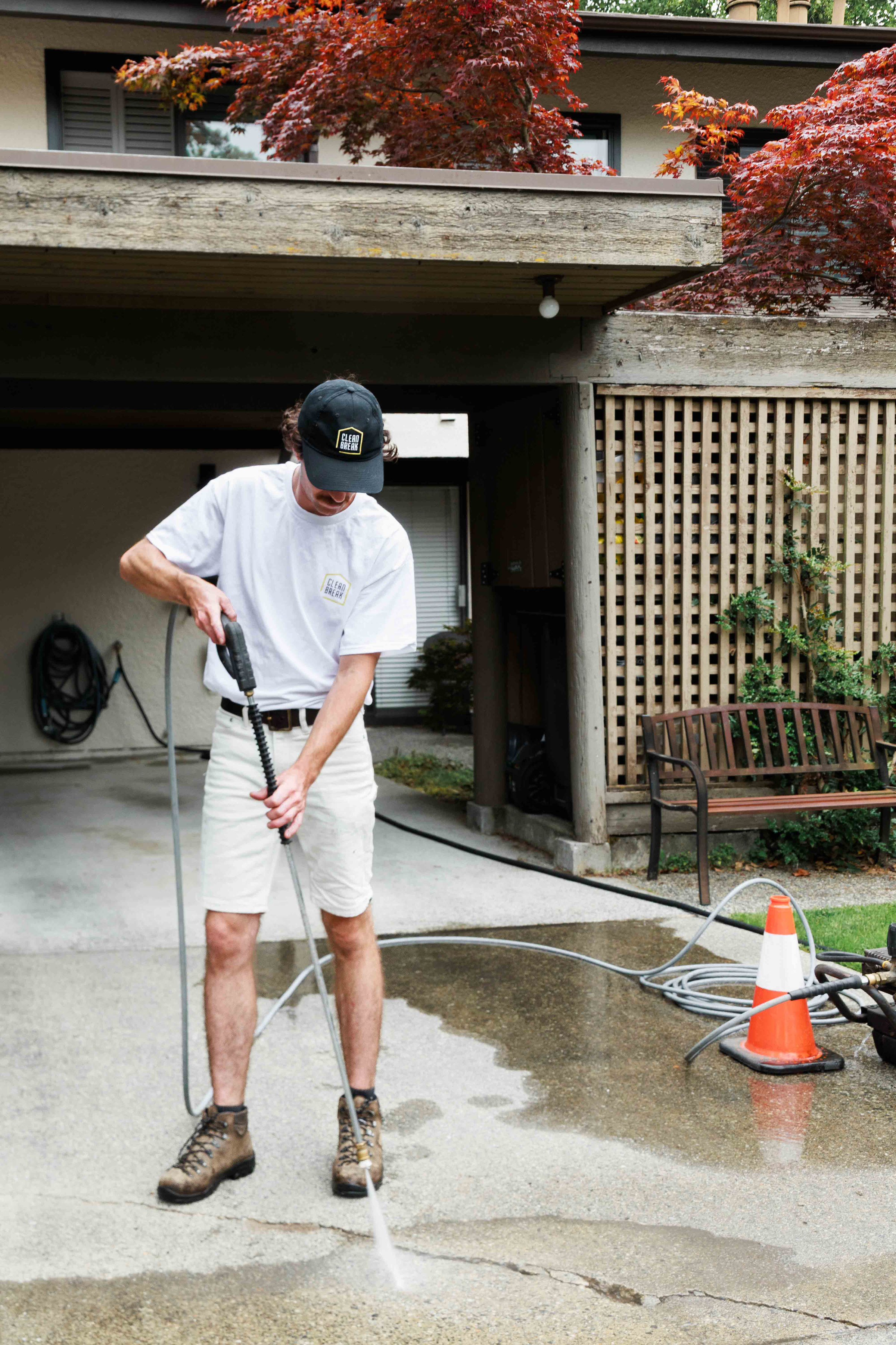 A Clean Break technician using a pressure washer to clean a residential driveway, showcasing professional concrete and surface power washing services in Vancouver and Richmond.