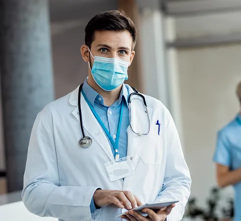 A clinician in a white coat holding a tablet