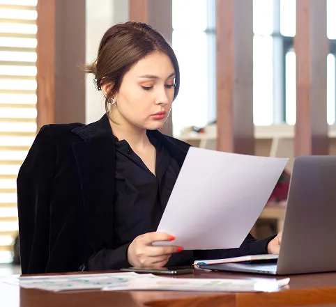 A professional reviewing documents at a laptop