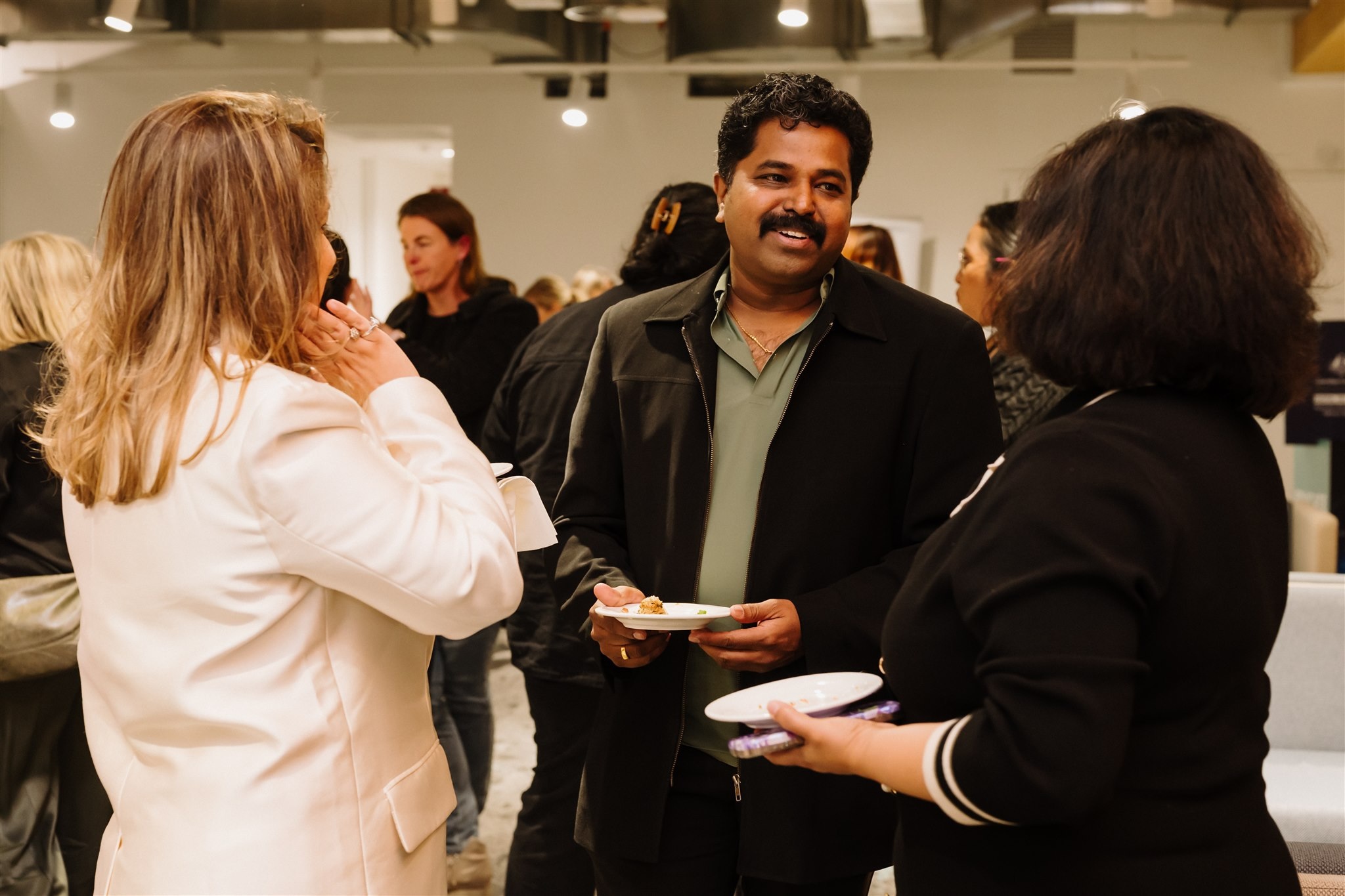 Melbourne Innovation Centre event attendees smiling together, two ladies facing away from the camera and a man with a moustache smiling at the camera