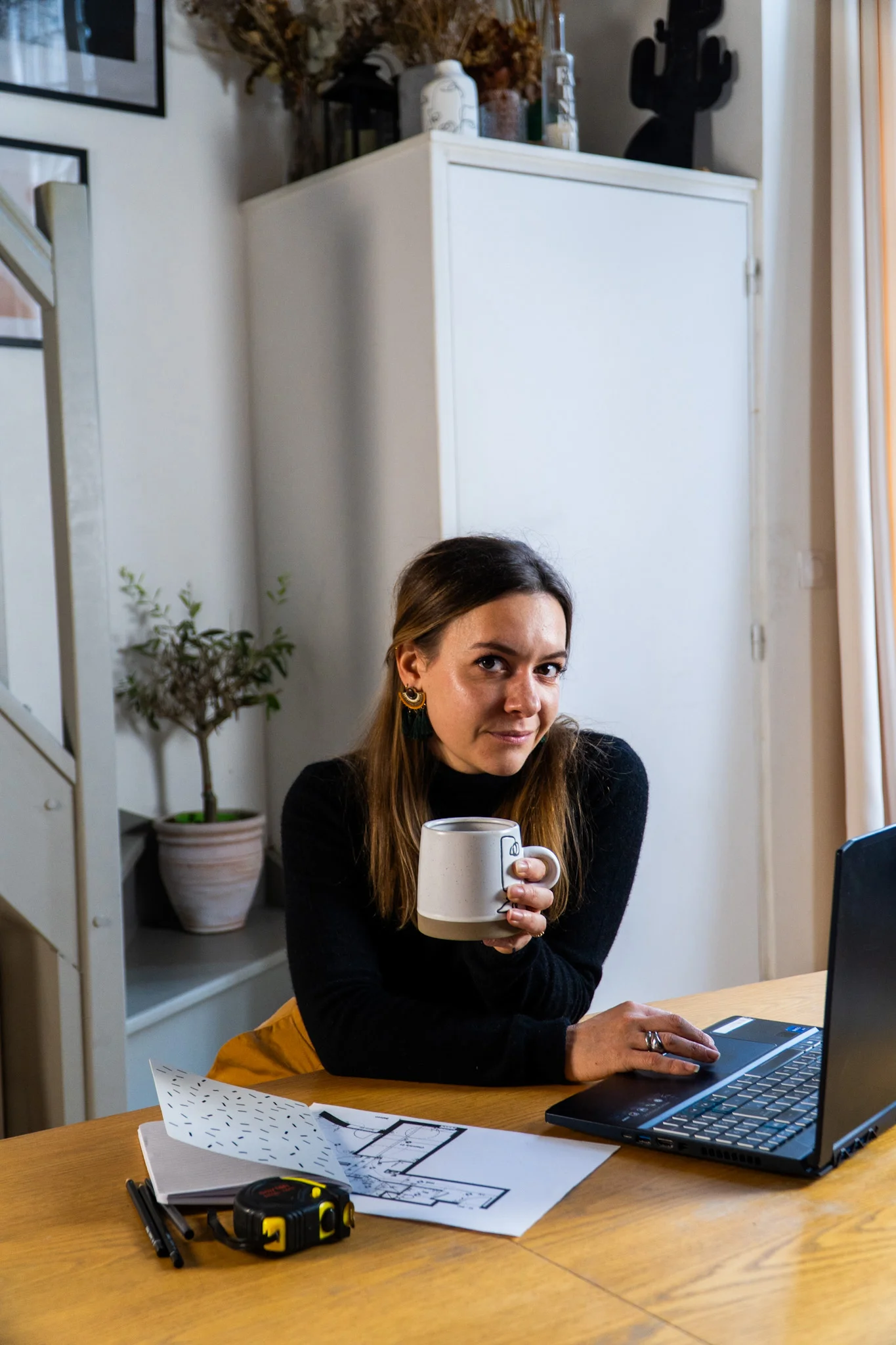 Architecte d’intérieur à son espace de travail, consultant des plans d’aménagement sur ordinateur portable.