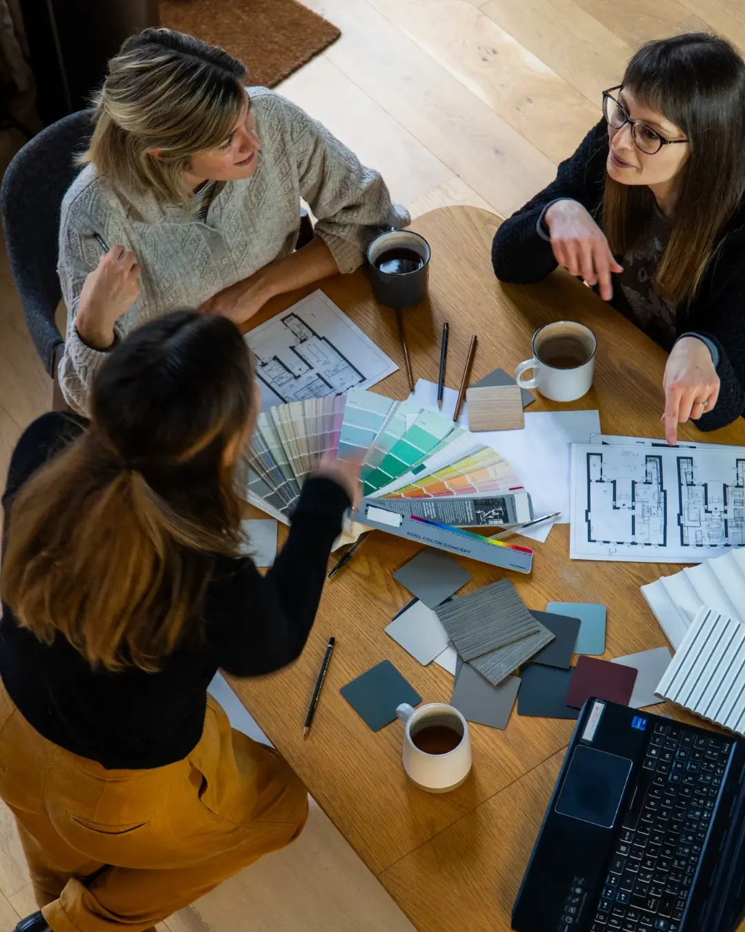 Atelier d’architecture d’intérieur avec sélection de couleurs, matériaux et plans d’aménagement autour d’une table de travail.
