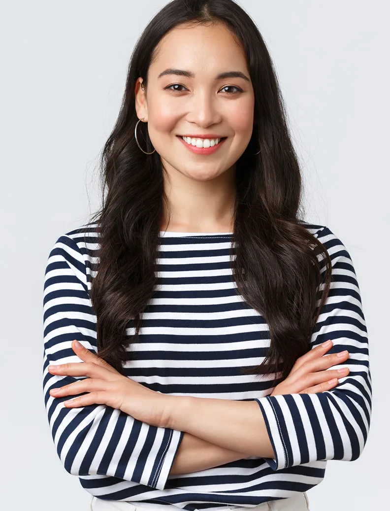 Smiling woman with long dark hair wearing hoop earrings and a navy and white striped shirt, arms crossed.