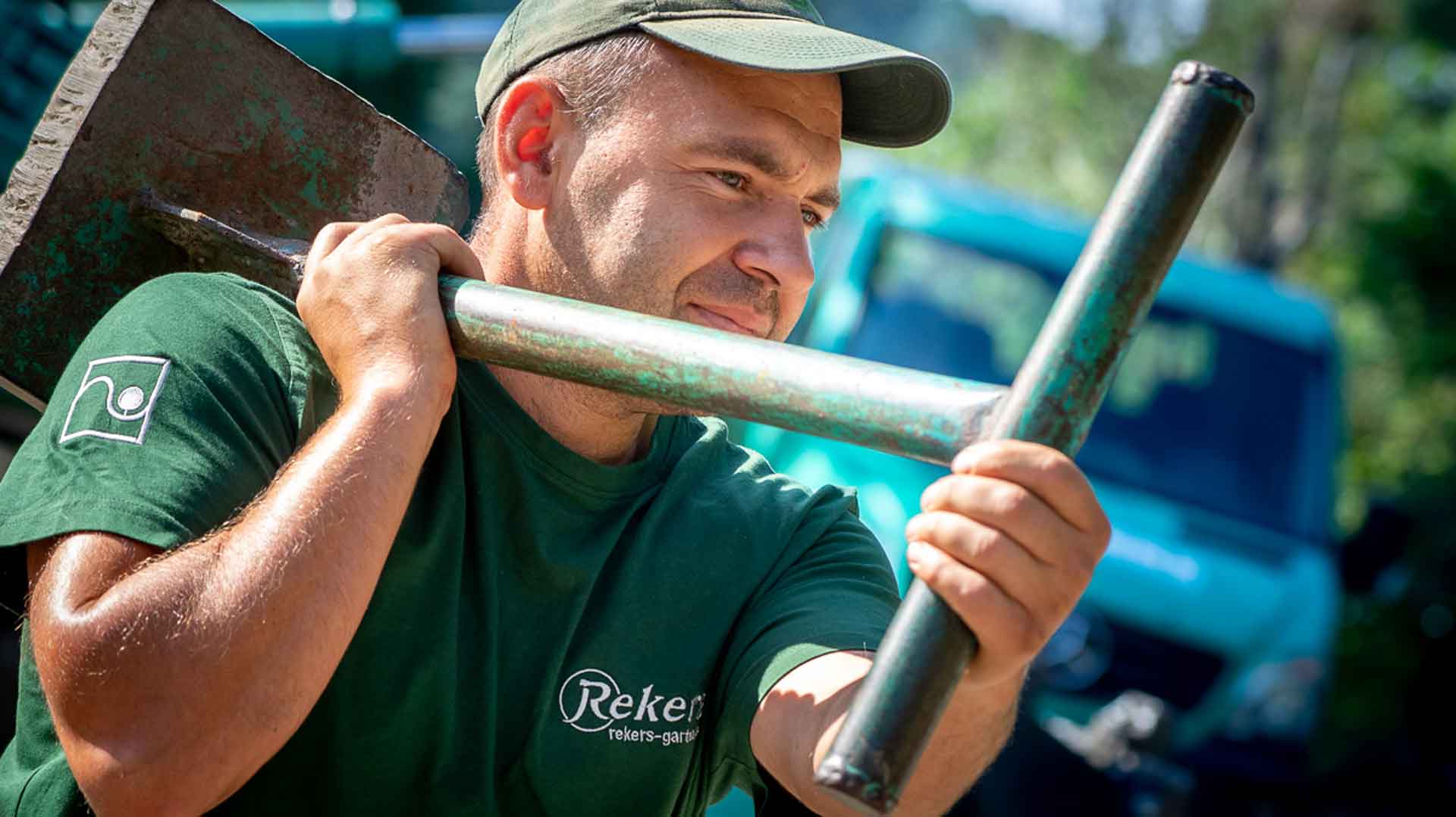 Mann trägt eine Schaufel auf der Schulter vor einem blauen LKW.