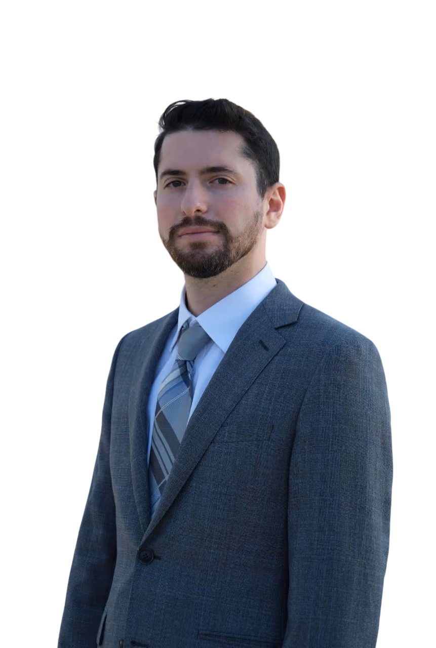 Man with beard wearing gray suit, light blue shirt, and striped tie looking at the camera.