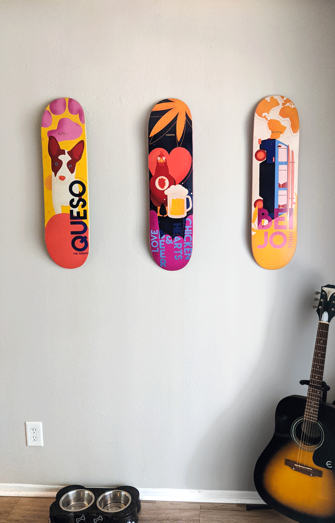 Three custom skateboard decks hanging on a wall, displayed as colorful decorative art.