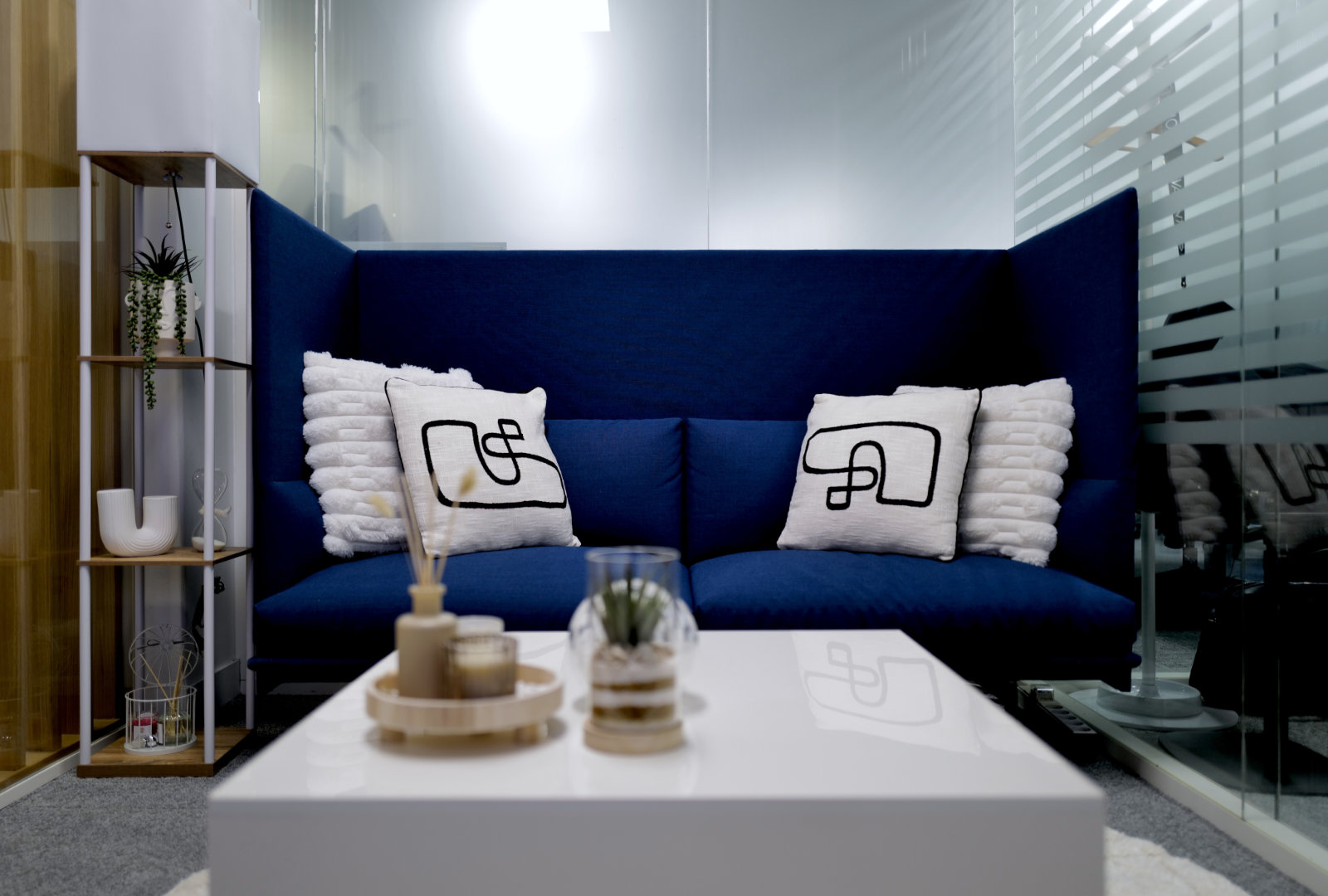 Espace lounge moderne du Studio TV Vendôme Saint-Honoré à Paris, avec canapé bleu et table basse design.