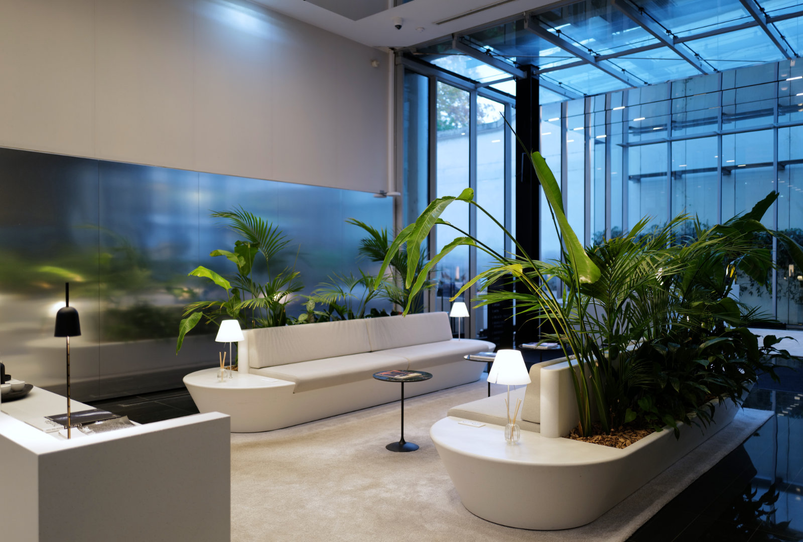 Espace d’accueil du Studio Vendôme Saint-Honoré à Paris, avec assises design et plantes vertes dans un hall lumineux.