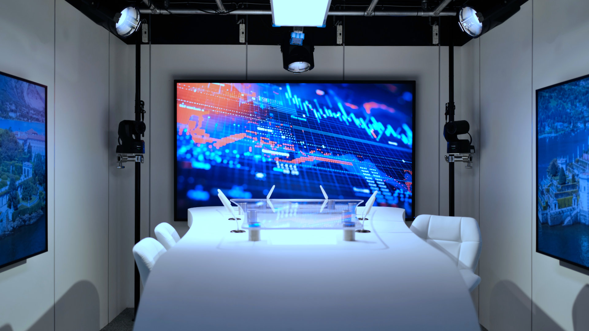 Modern conference room with white chairs and a curved table facing a large screen displaying colorful financial charts.