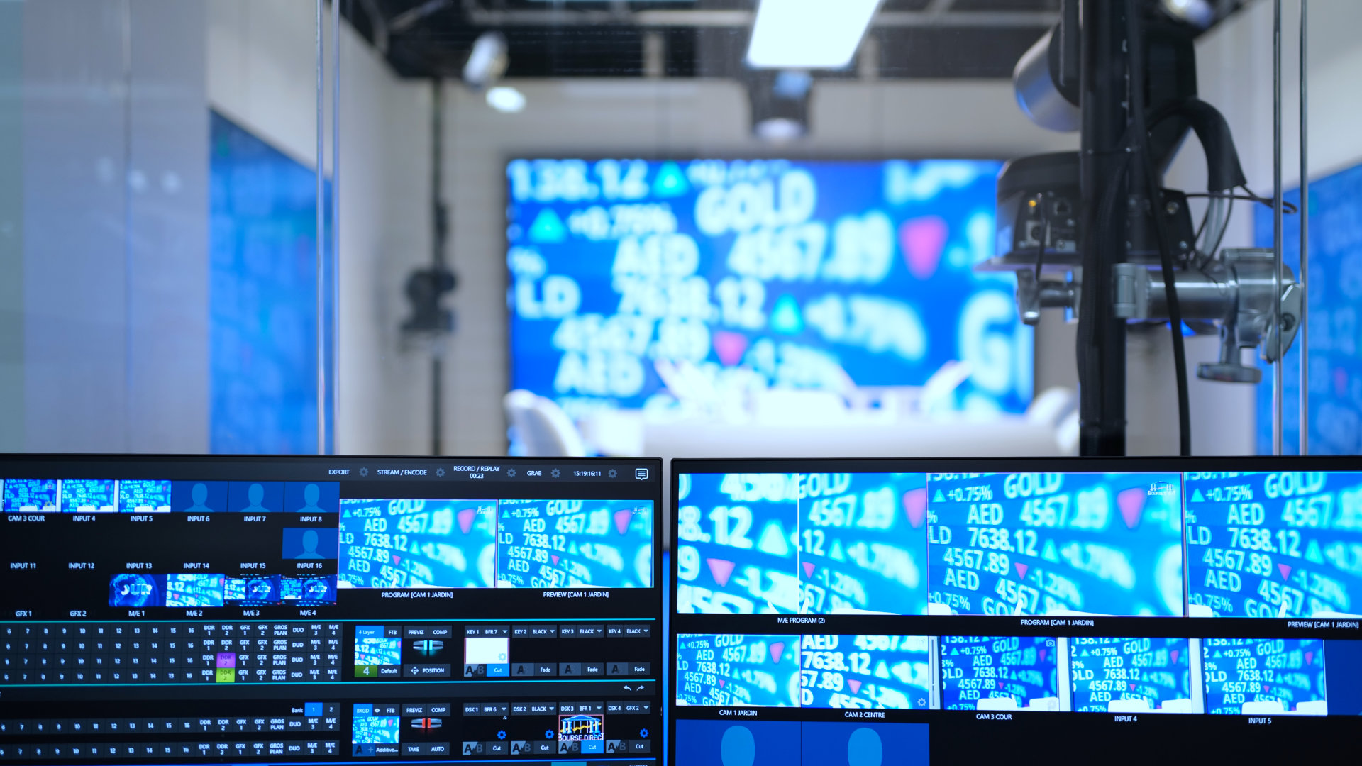 Close-up of a broadcast control room screen showing multiple video feeds of stock market data with blue backgrounds and financial figures.