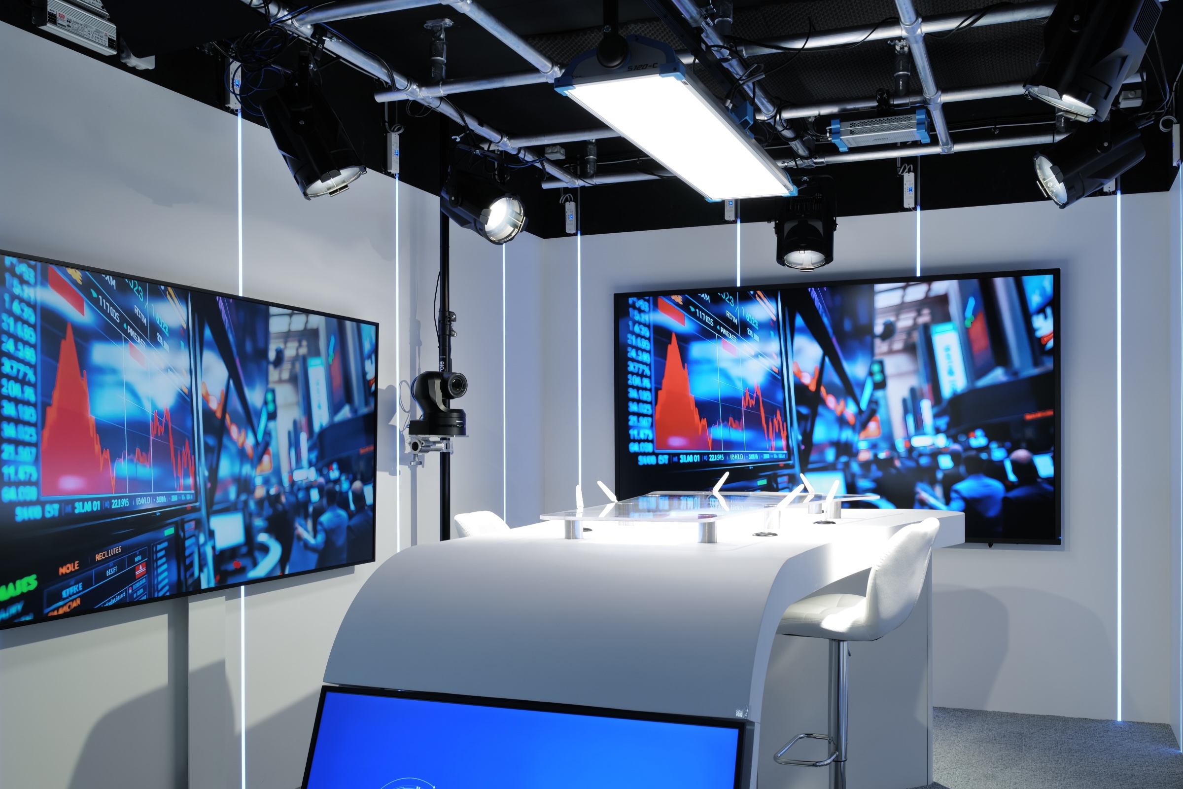 Studio TV professionnel
Vendôme Saint-Honoré setup with two large screens displaying stock market graphs and a white curved table with a microphone and a chair.