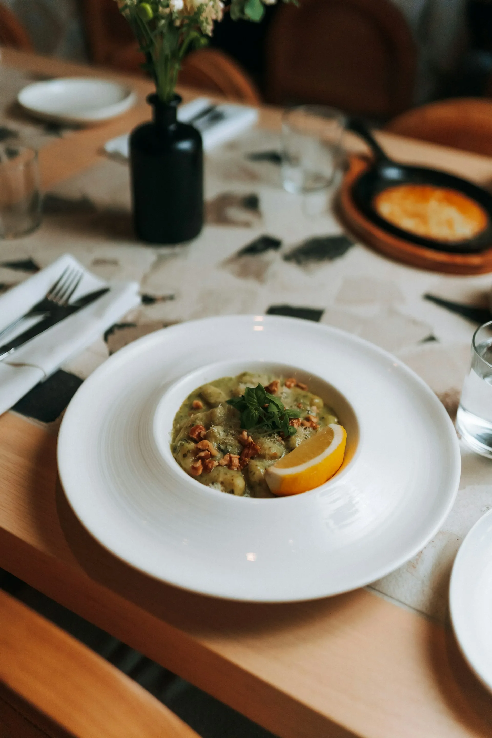 A white plate topped with a bowl of soup next to a glass of water.