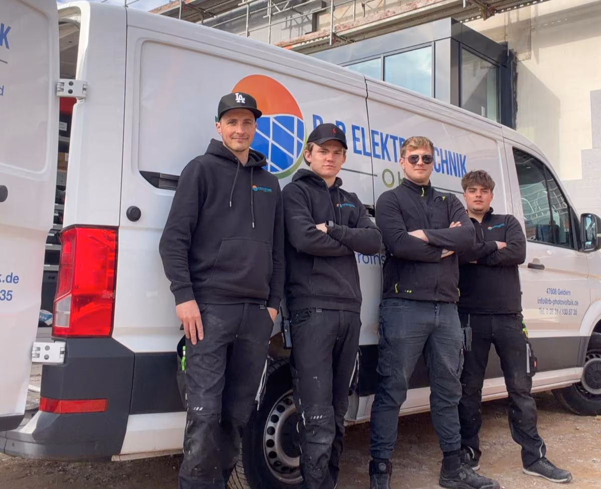 Team am Firmenwagen von R+B Elektrotechnik vor einer Gewerbehalle