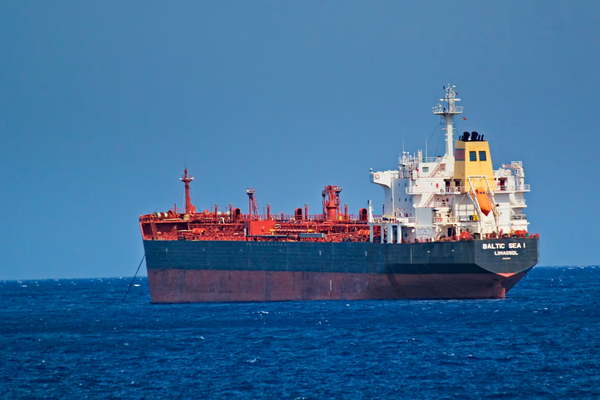 Large cargo ship named Baltic Sea I anchored in calm blue ocean under a clear sky.