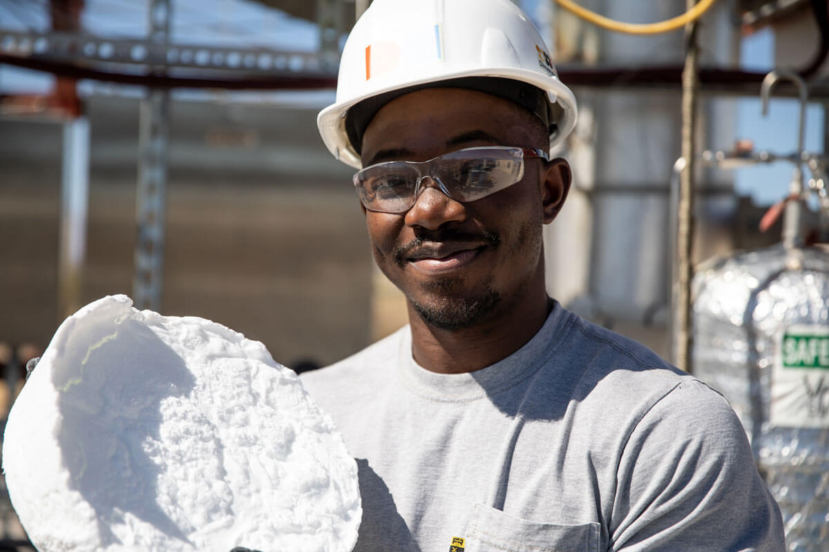 Gloved hands hold a large wax wafer.