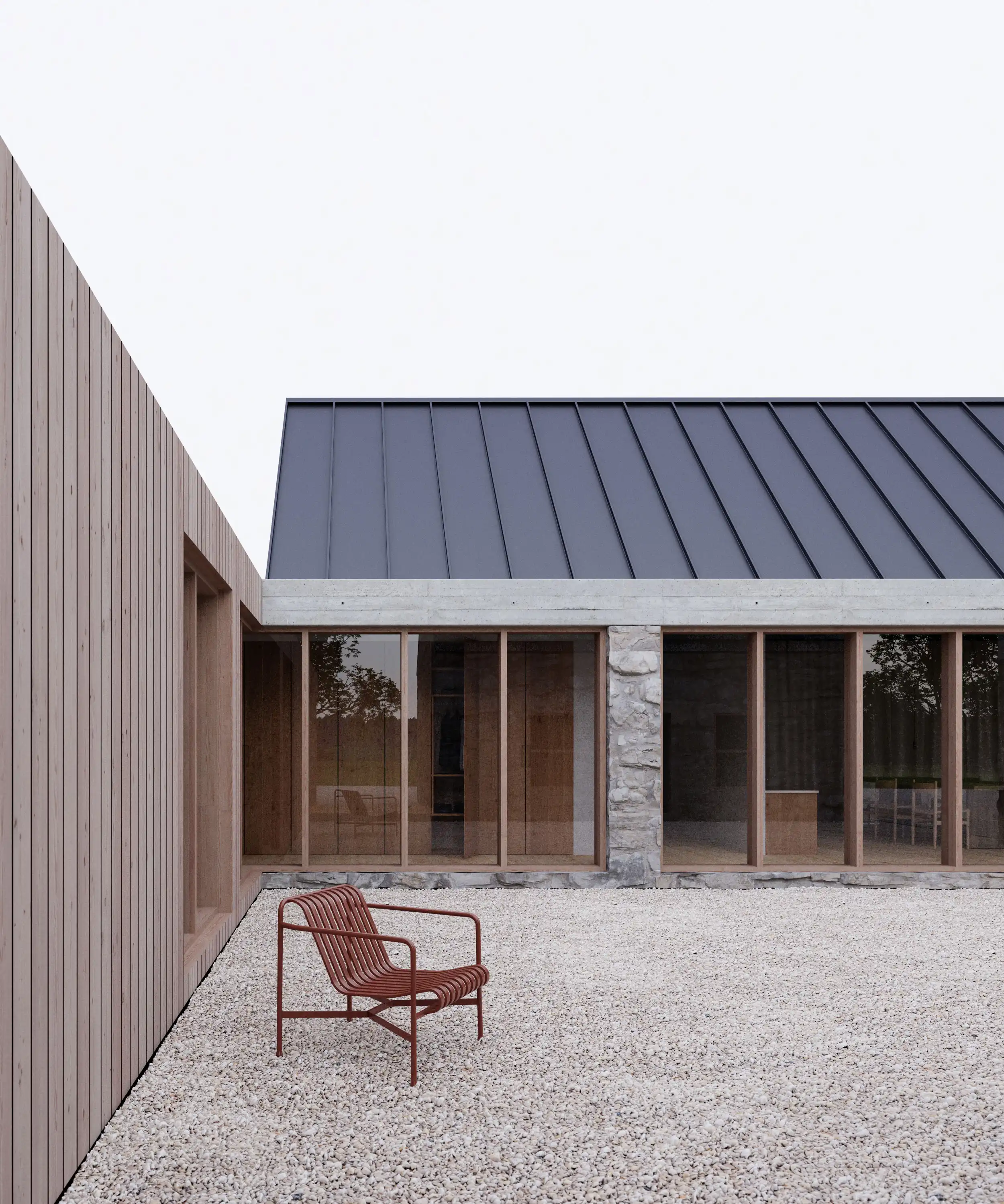 Modern courtyard with gravel ground, one maroon metal chair, wood-paneled wall on left, and building with large windows and dark angled roof.