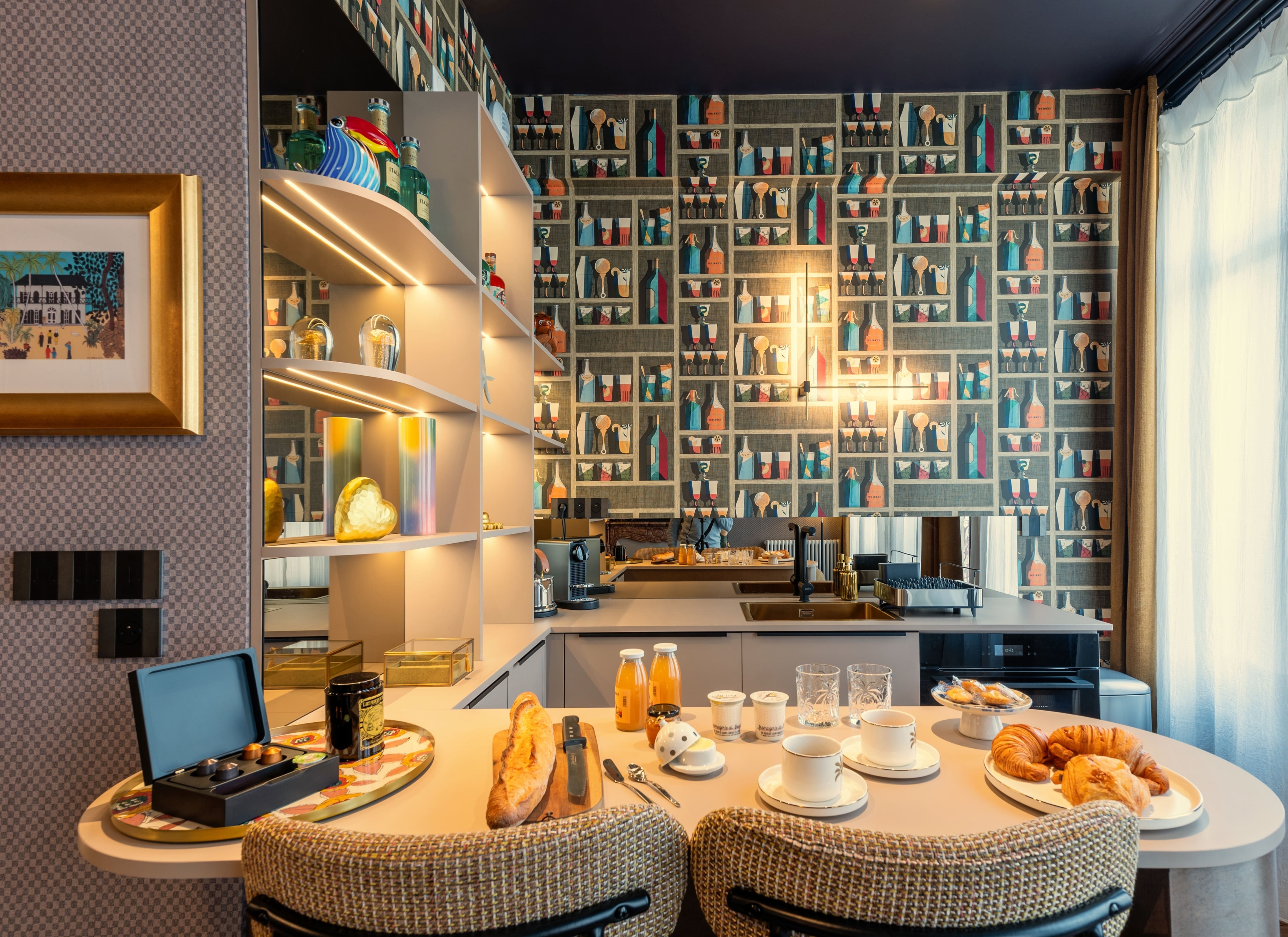 Cuisine moderne avec comptoir de petit-déjeuner servi avec croissants, baguette, tasses de café et jus d'orange.