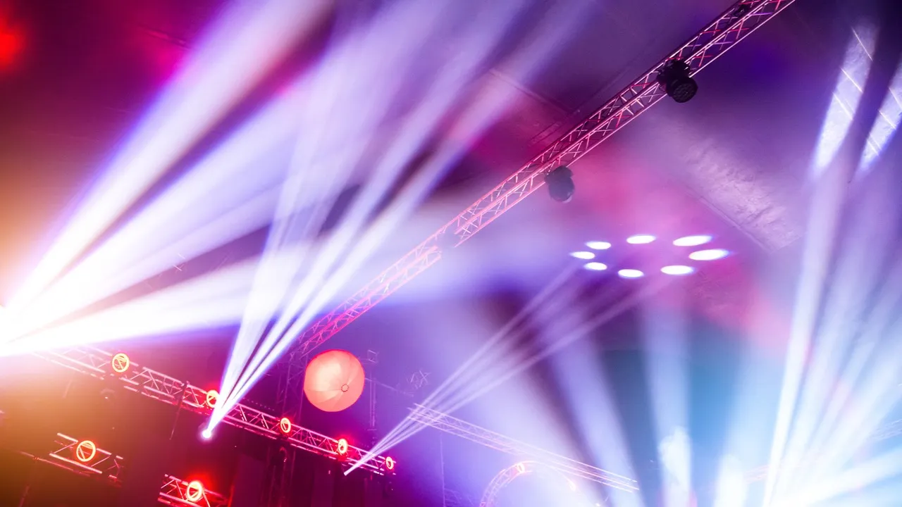 Bright white and red stage lights shining and creating beams in a concert or event setting.