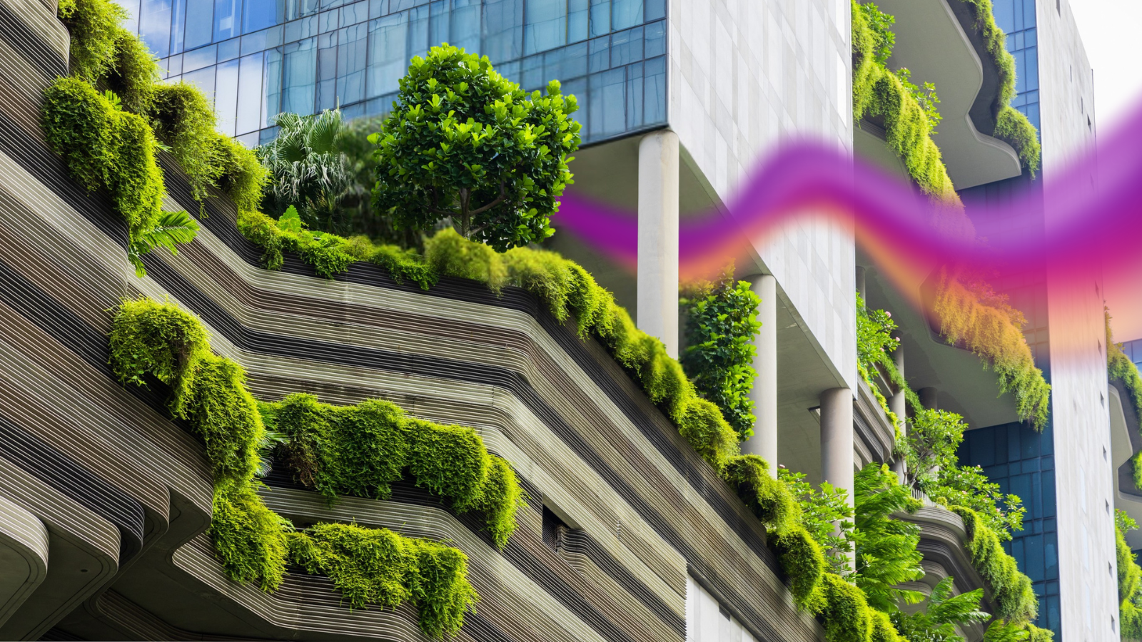 Modern building with balconies and terraces covered in lush green plants and trees, featuring a mix of concrete and glass architecture.
