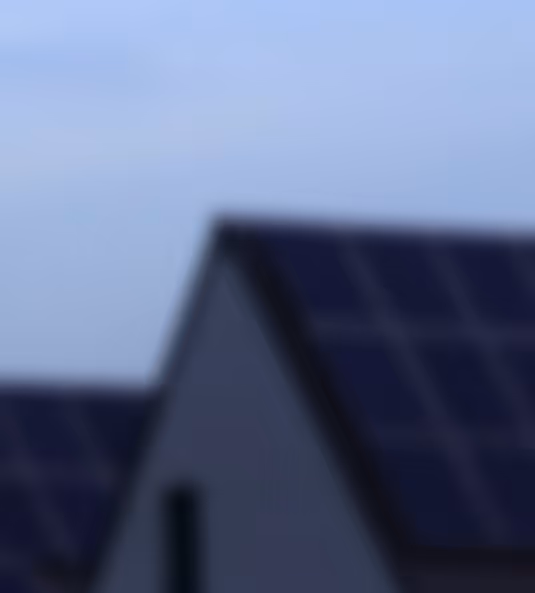 Unscharfe Aufnahme von einem Hausdach mit Solarpaneelen bei Tageslicht.