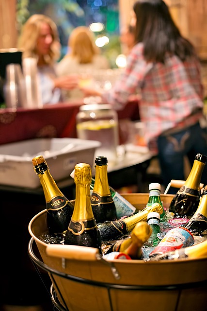 Wooden bucket filled with ice and multiple bottles of champagne and beer at a social gathering.