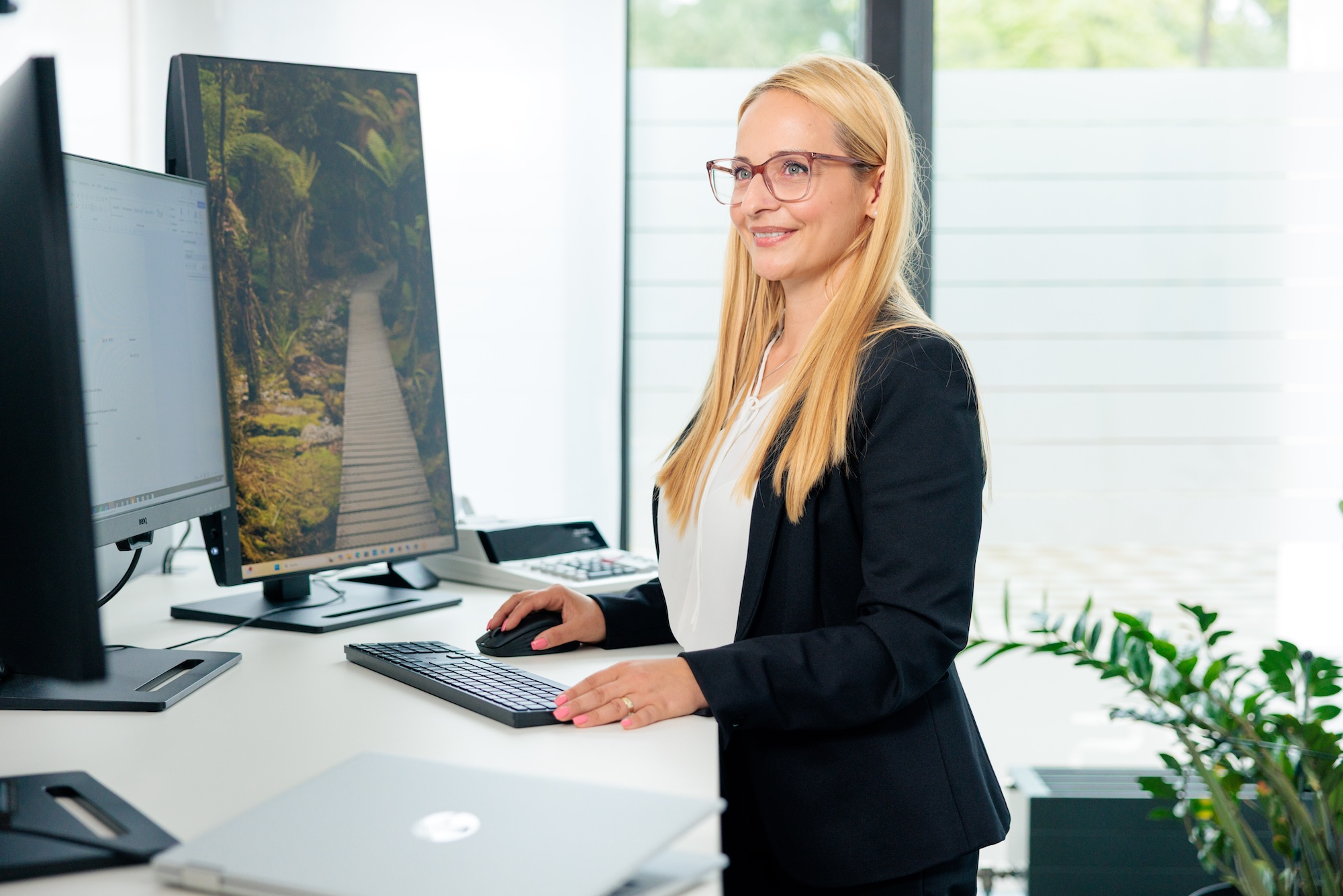 Mitarbeiterin arbeitet an zwei Monitoren im hellen Kanzleibüro