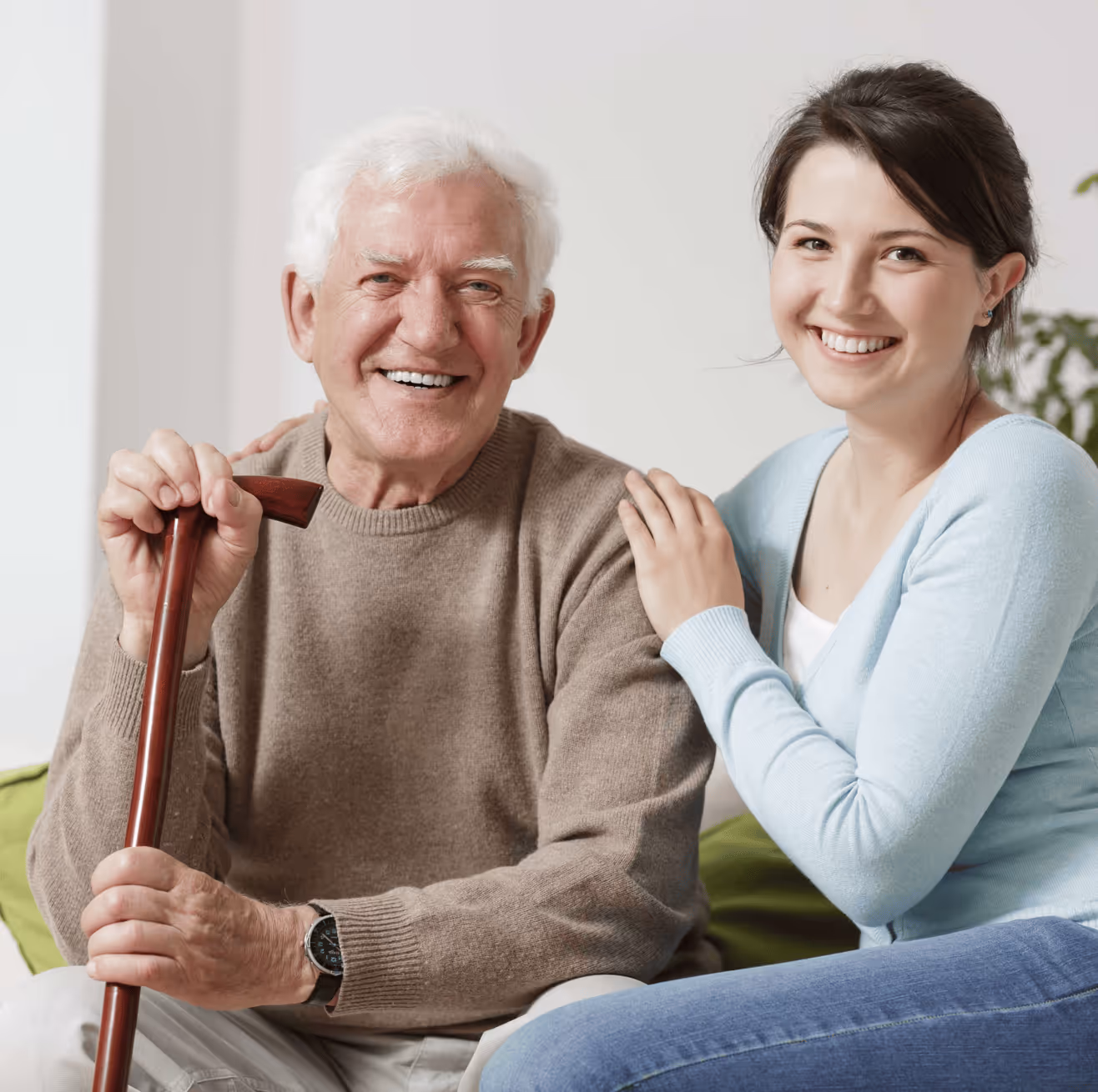 Older man holding a cane with a supportive family member sitting next to him