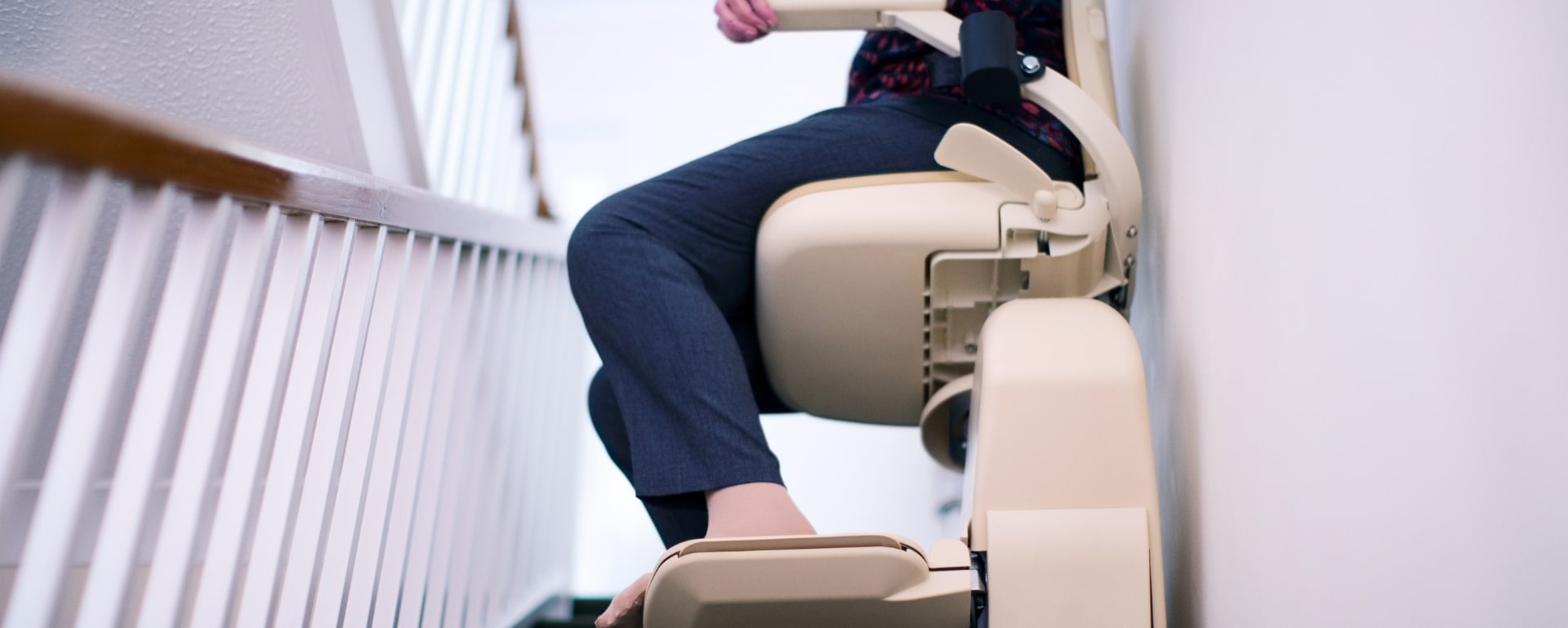Close-up of a person riding a stairlift chair along a home staircase