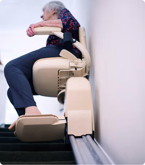 Older adult riding a stairlift up a home staircase for safe and independent mobility