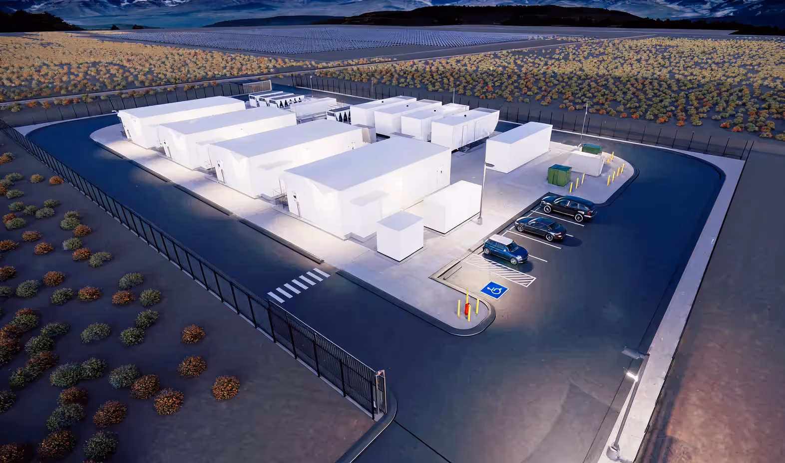 Aerial view of a fenced modular data center with parked cars, handicap space, and surrounding desert vegetation.