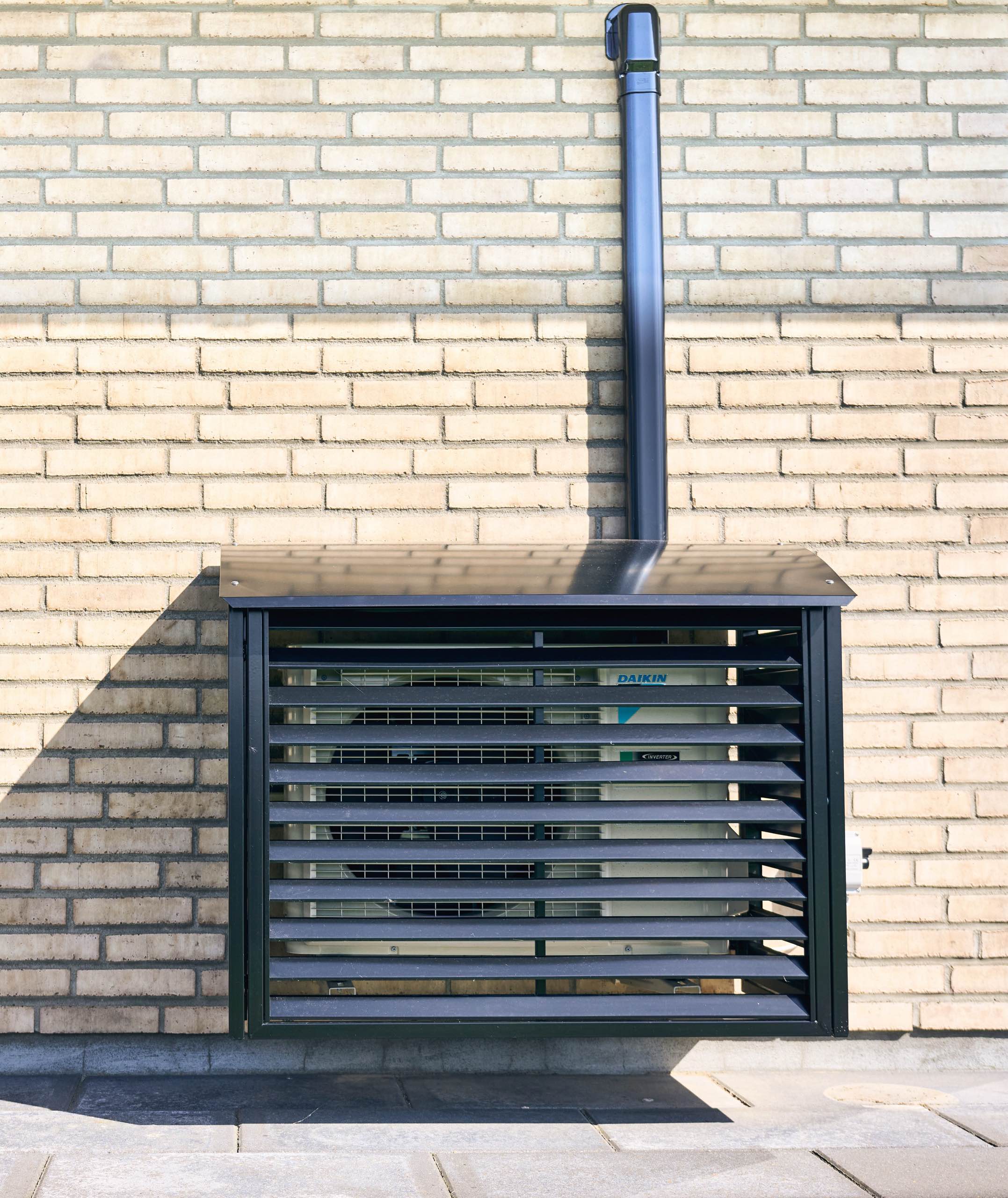 Den udvendige del af en varmepumpe monteret på en gul murstensvæg