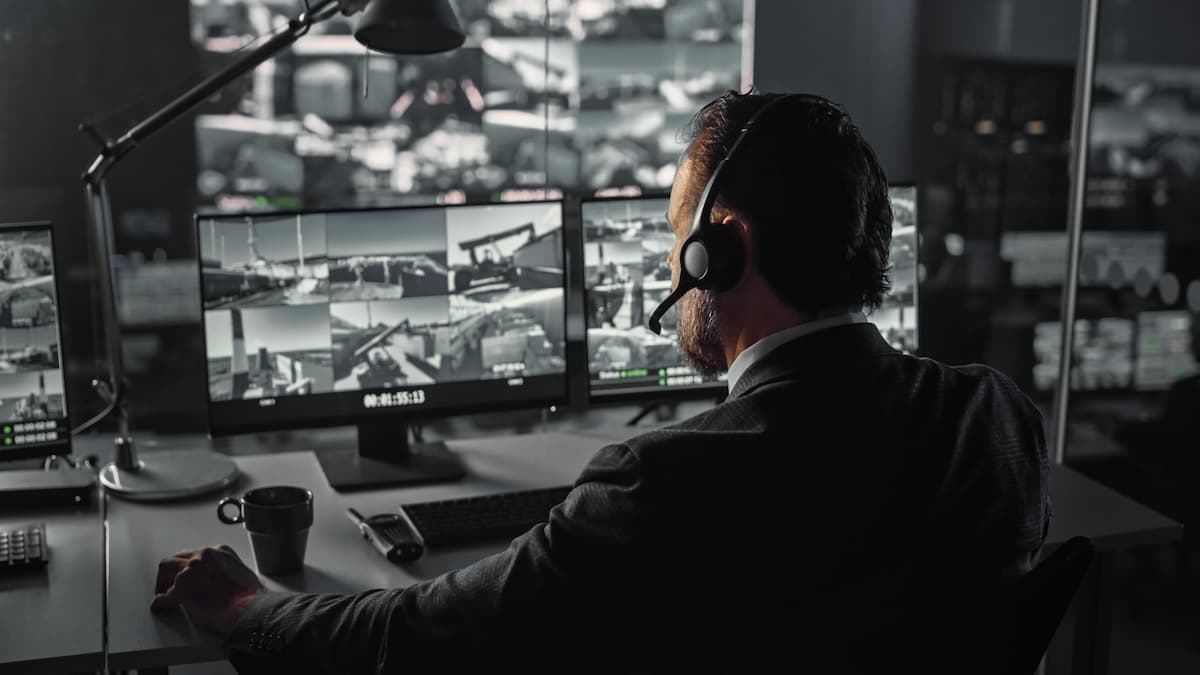 Security monitoring professional reviewing live camera feeds in a 24/7 monitoring center.