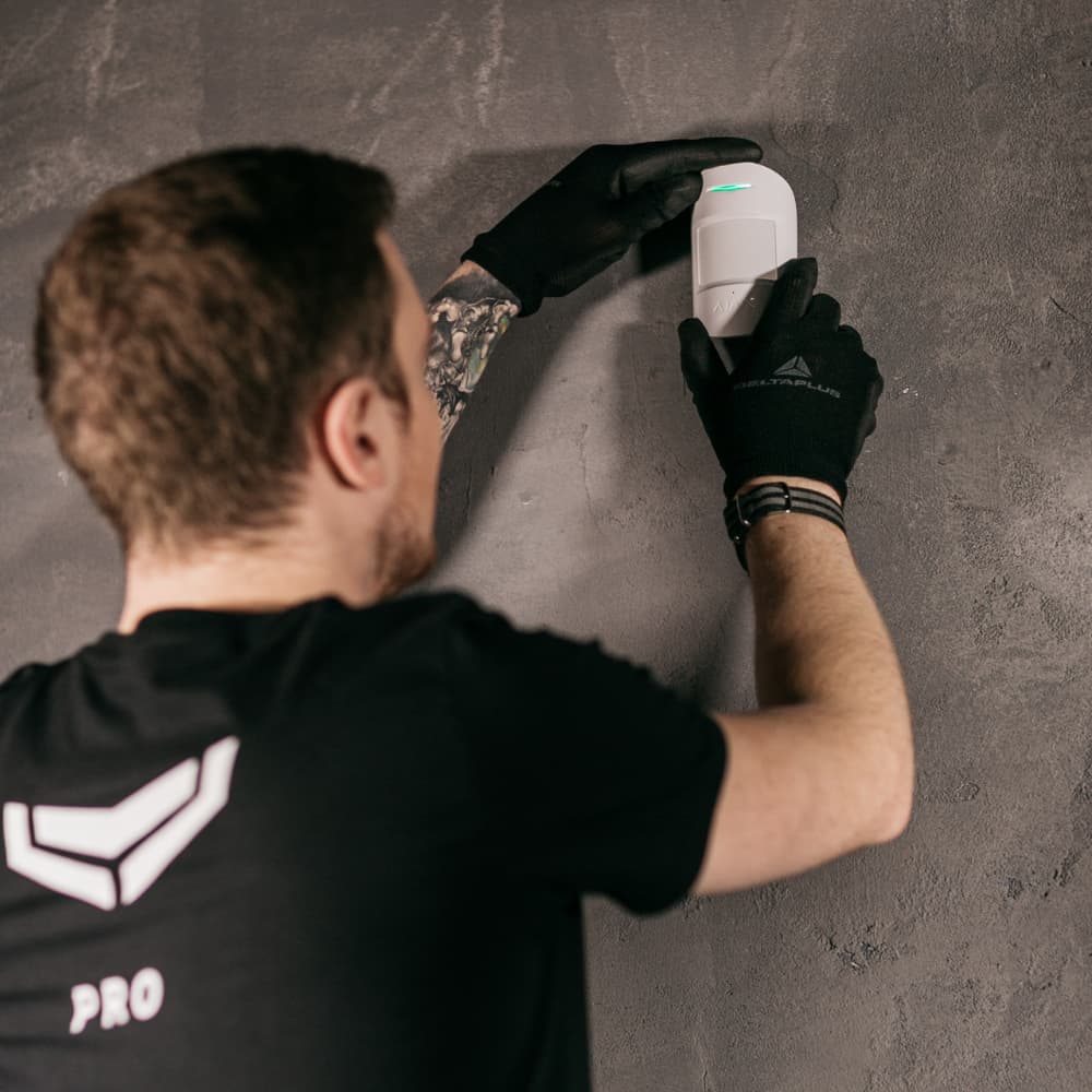 Professional security technician installing an Ajax motion sensor during system setup