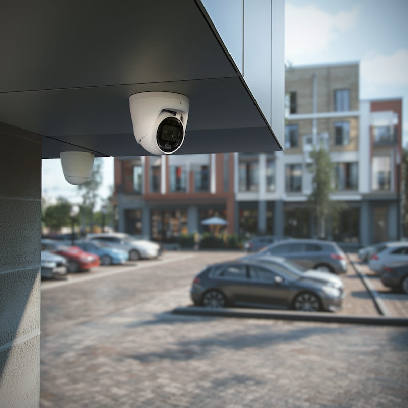 Outdoor security camera monitoring driveway, garage, vehicle areas, and parking lot activity